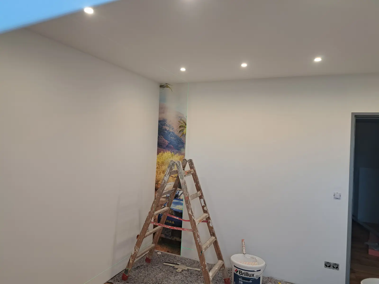 Erste Tapetenbahn an der Wand, mit Laserlinie ausgerichtet
